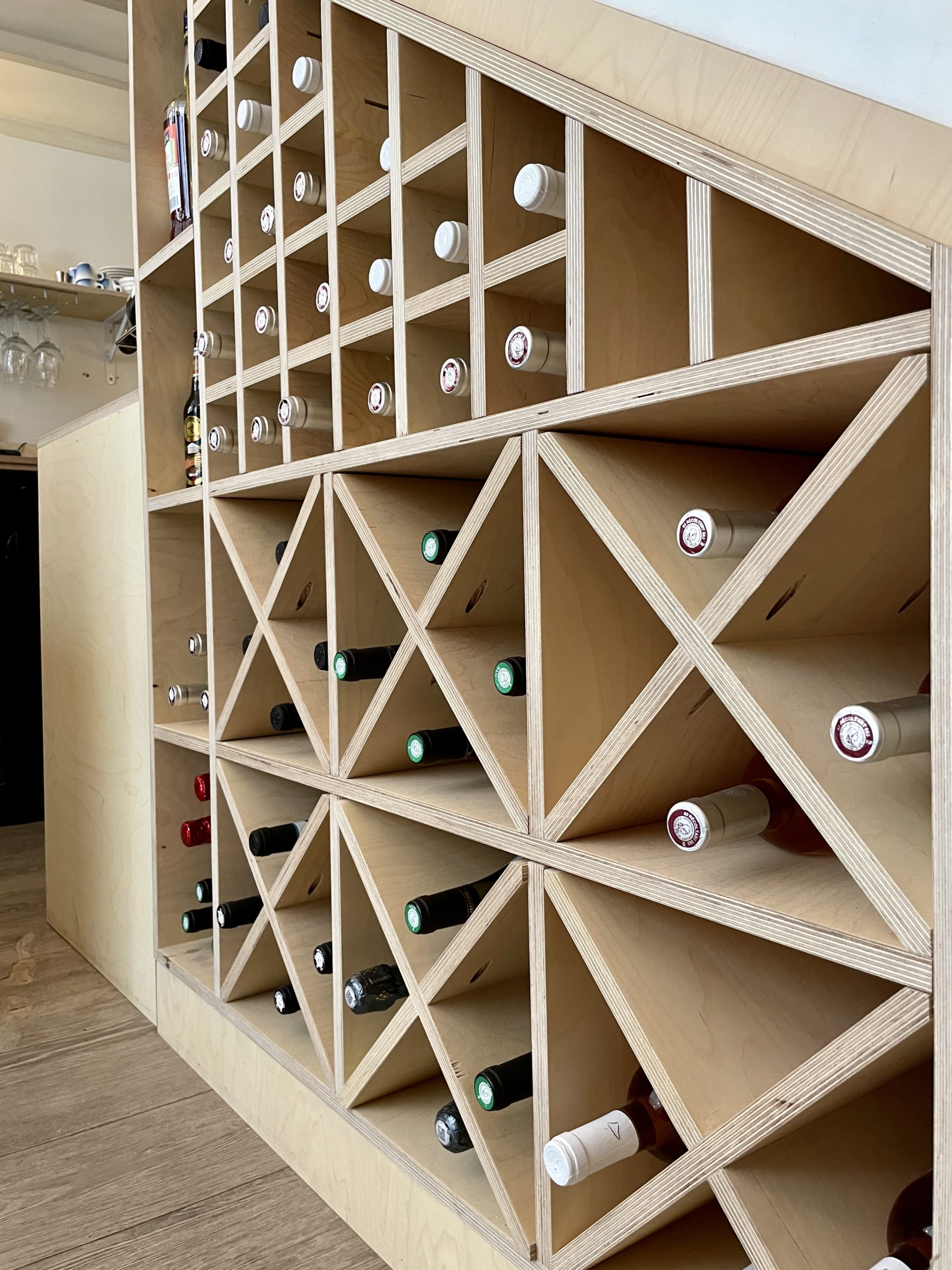 Agencement sur mesure de casier à vin en bois pour l'optimisation de l'espace de service en intégrant le dessous de l'escalier.